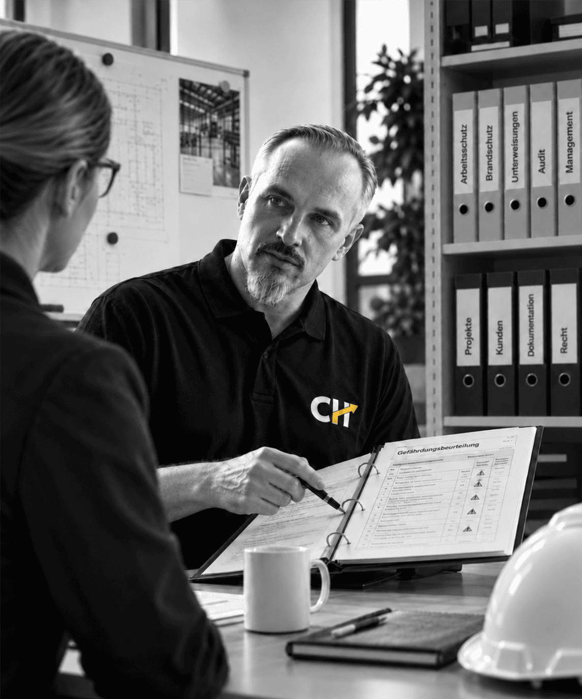 Christian Harrer bei der Prüfung einer Gefährdungsbeurteilung im Gespräch mit einer Mitarbeiterin – strukturierte Arbeitsschutzorganisation und praxisnahe Dokumentation im Unternehmen.